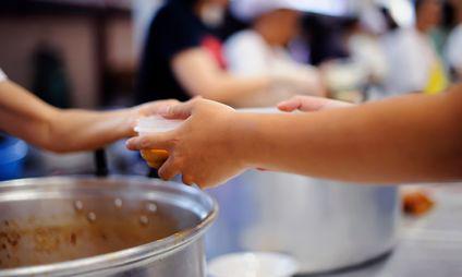 Close up of hands of a woman receiving a plastic bowl in a food canteen.